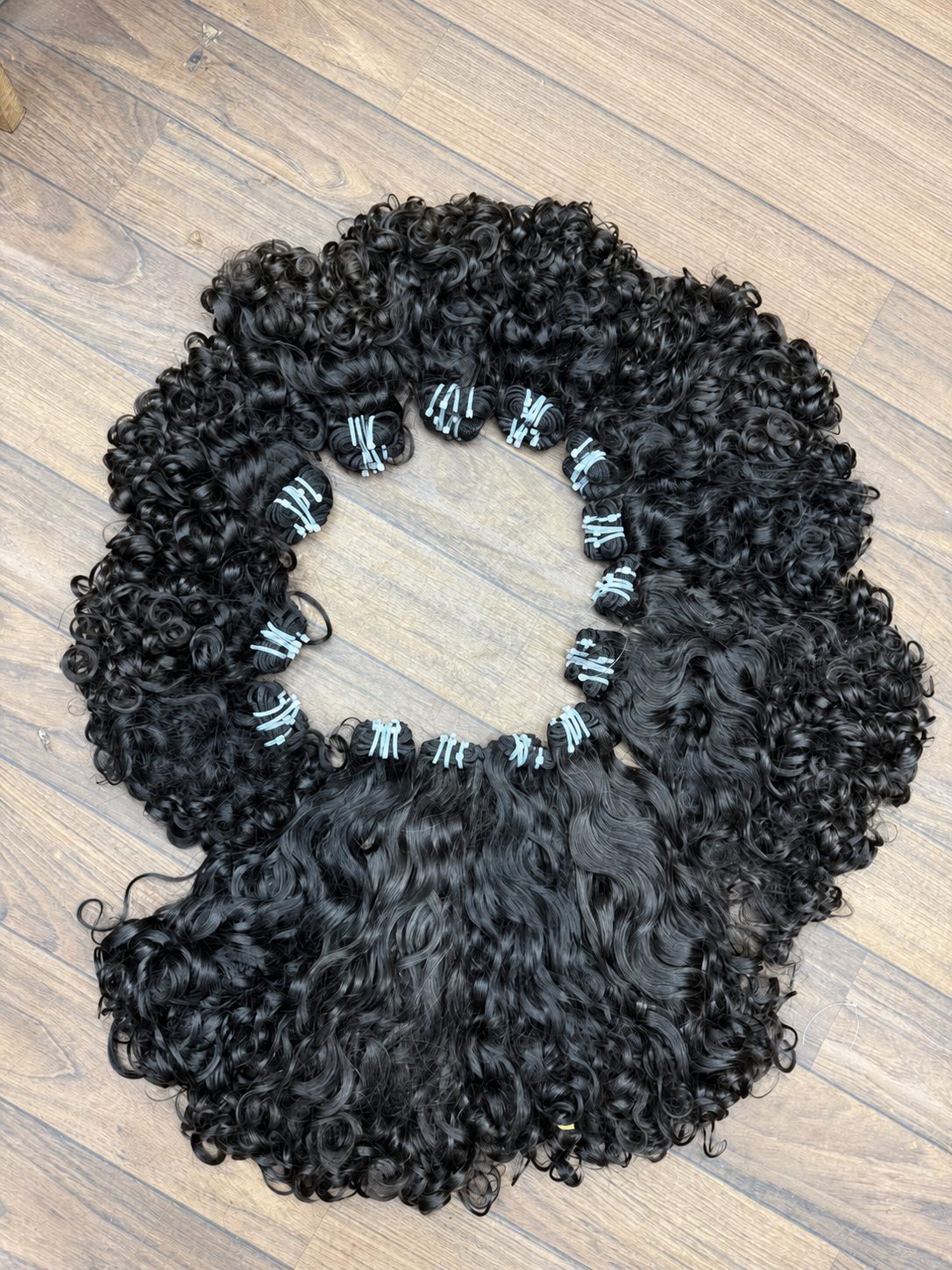 Mèches baby hair bouclées sur fond bois épuré